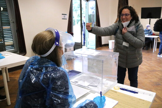 A woman pulling down her face mask to be identified during the election rehearsal in Terrassa (by Albert Segura Lorrio)